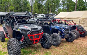 Four Adventure Club's Polaris ATVs are parked in the woods..