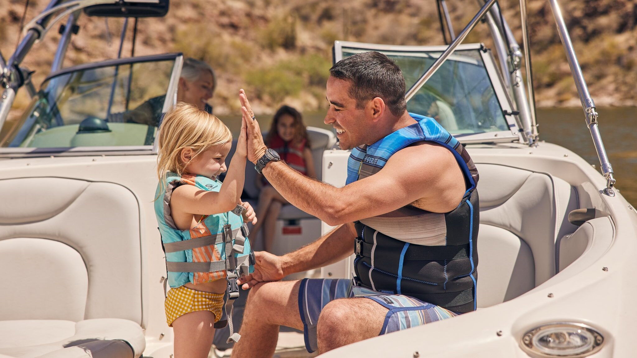 A father teaches his daughter about boating safety and the need for safety jackets.